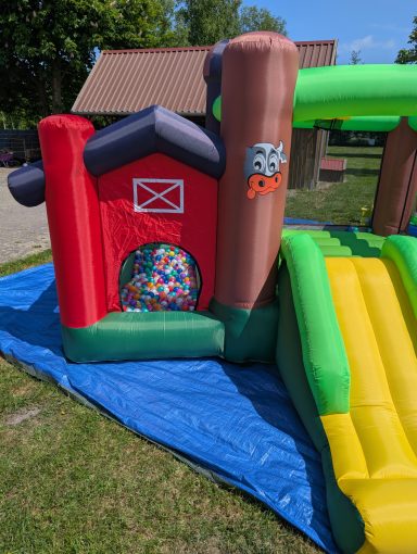 Bunte Hüpfburg mit Rutsche, angrenzend an einen Bereich mit bunten Bällen.
